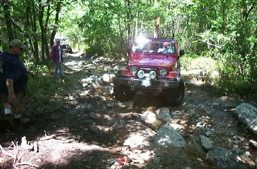 Red Jeep traversing rocky trail