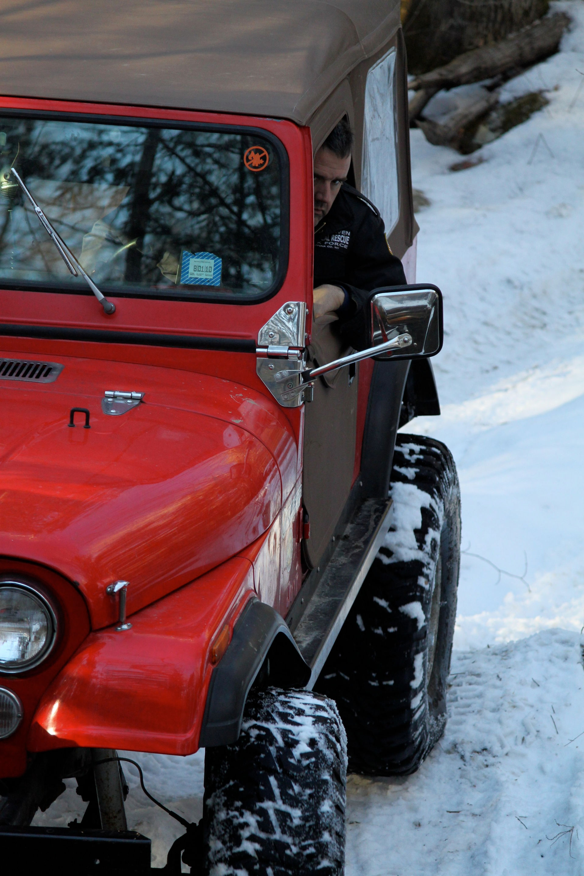 Man exiting red Jeep in snowy terrain