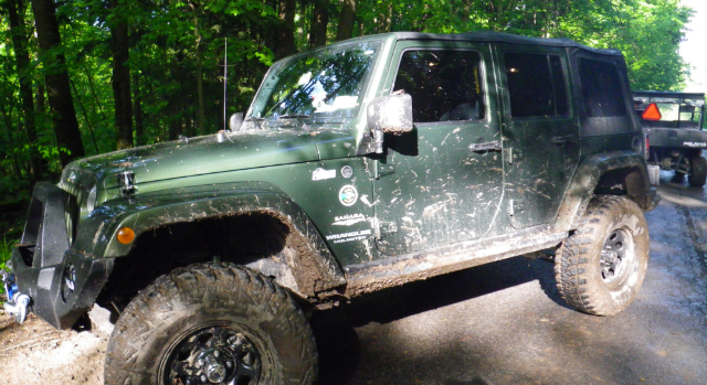 Muddy green Jeep Wrangler off-road