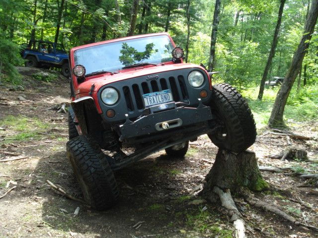 Red Jeep traversing a wooded trail