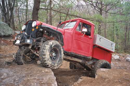 Woman driving a red Jeep truck off-road