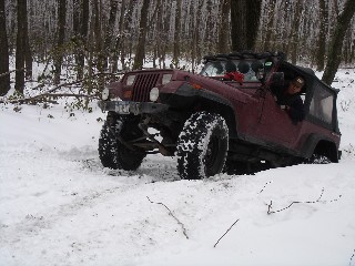 Man driving red Jeep Wrangler in snowy woods
