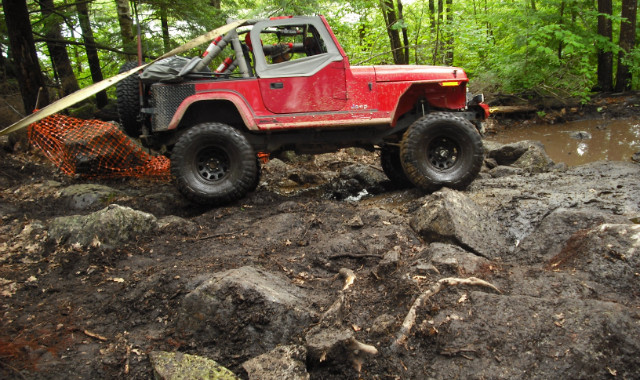 Red Jeep navigating rocky terrain