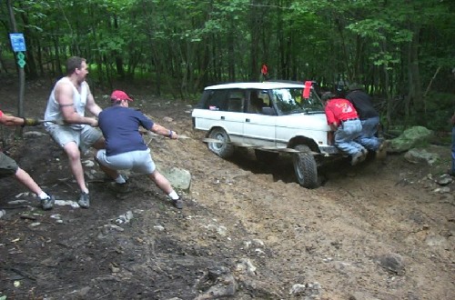 Men pushing stuck Range Rover in woods
