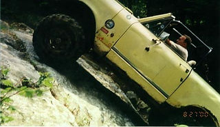 Muddy yellow International Scout traversing stream