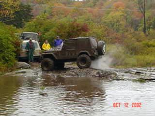 Jeep traversing rocky stream, off-road adventure