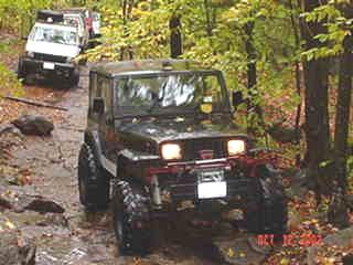 Black Jeep Wrangler off-roading on a muddy trail