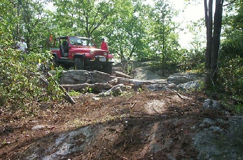 Red Jeep navigating rocky terrain