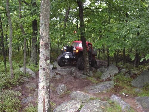 Red Jeep navigating rocky terrain