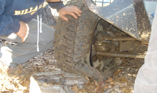 Person inspecting muddy off-road tire