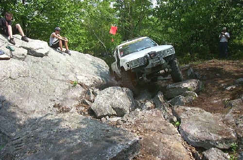 White truck rock crawling, person watching