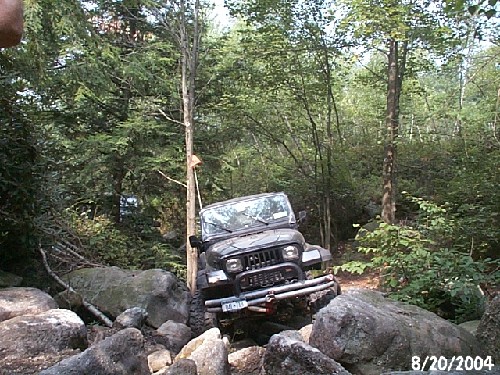 Jeep navigating rocky trail in woods