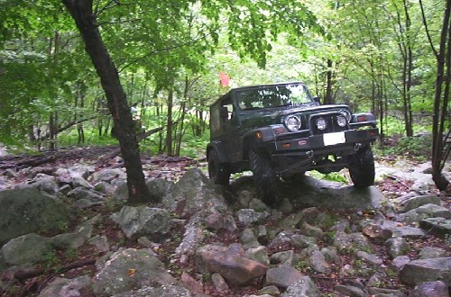 Green Jeep navigating rocky terrain