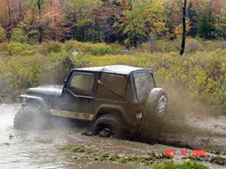 Black Jeep traversing muddy trail