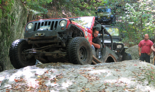 Red Jeep navigating rocky off-road trail