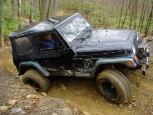 Black Jeep navigating muddy off-road trail