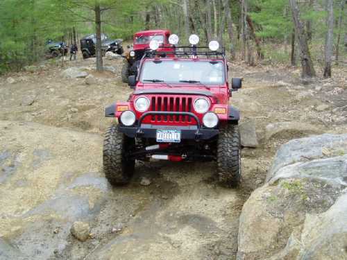 Red Jeep navigating rocky off-road trail