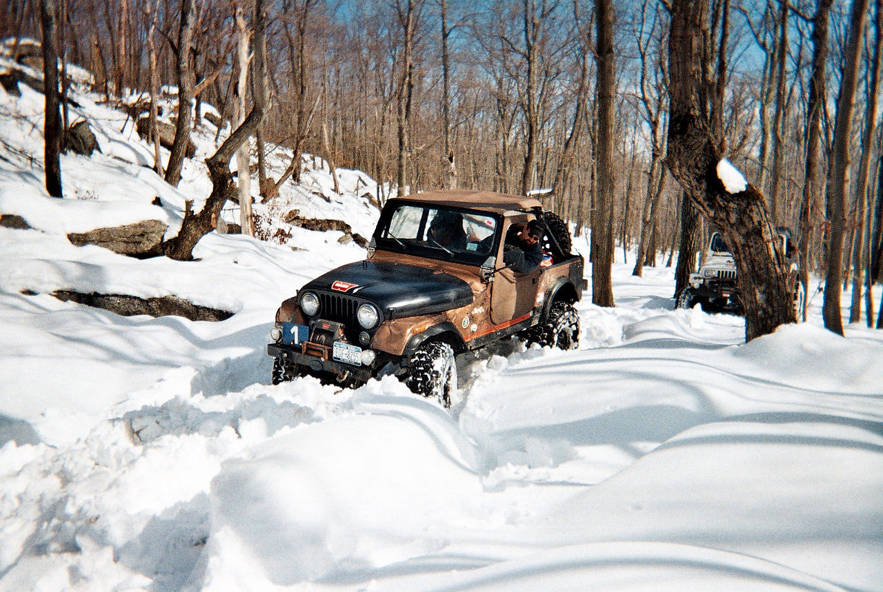 Jeep plowing through snowy trail