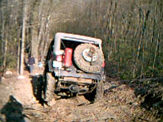 Jeep traversing muddy woodland trail