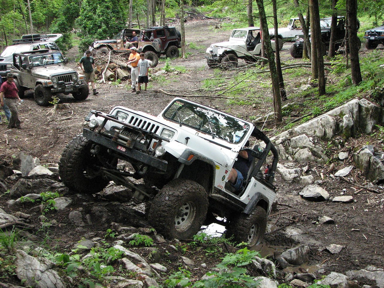 White Jeep navigating rocky terrain during off-road event