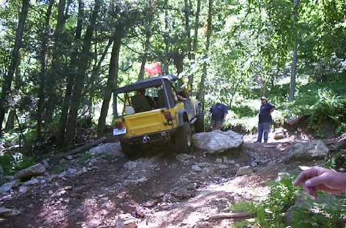Yellow Jeep navigating rocky terrain