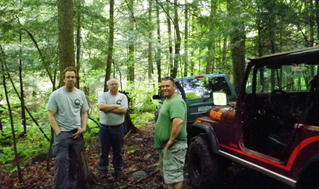 Three men and Jeep in woods