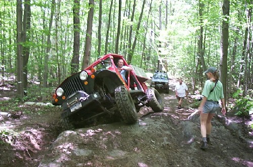 Red Jeep navigating rocky trail, off-road adventure