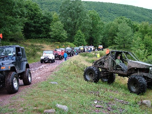 Off-road vehicles line a muddy trail