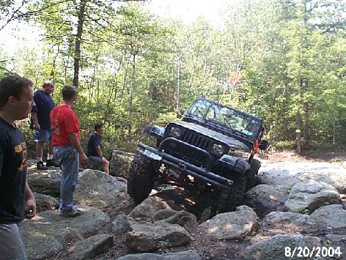 Jeep navigating rocks; onlookers watch