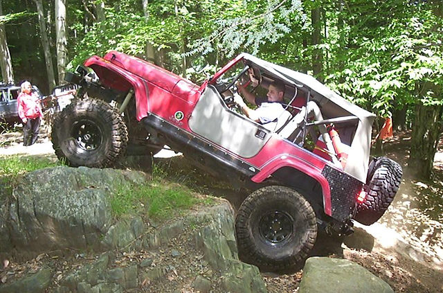 Man driving red Jeep on rocks