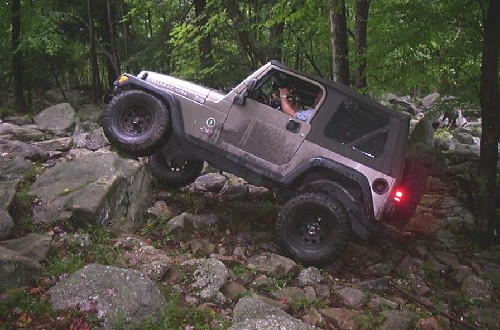 Man driving Jeep over rocks