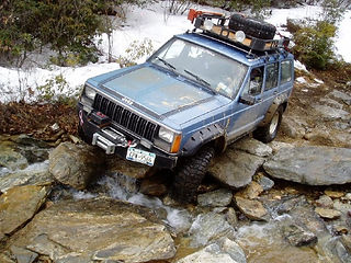 Blue Jeep Cherokee navigating rocky terrain