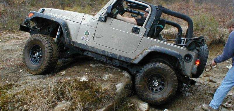 Tan Jeep Wrangler navigating rocky terrain