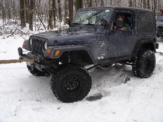 Person driving Jeep in snowy woods