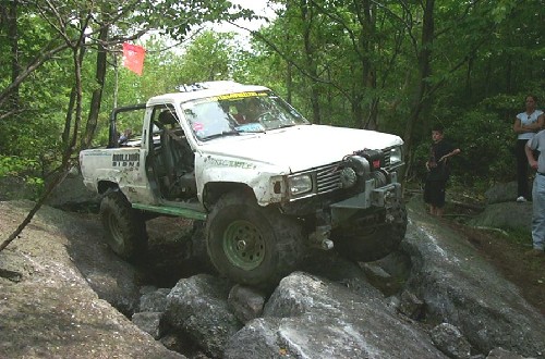 White Toyota pickup truck navigating rocky terrain