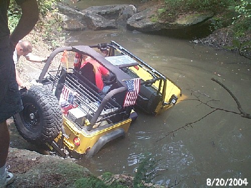 Yellow Jeep submerged in creek bed