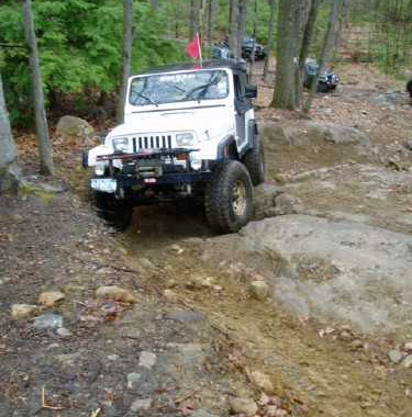 White Jeep navigating rocky off-road trail