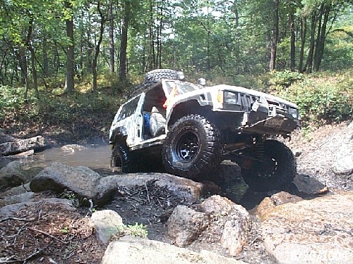 White Jeep traversing rocky stream bed