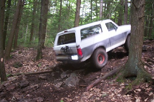 White Ford Bronco traversing rocky forest trail
