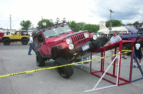 Red Jeep overcoming obstacle at Long Island Off Road event
