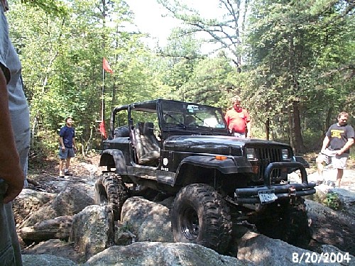 Black Jeep traversing rocks; two men watching