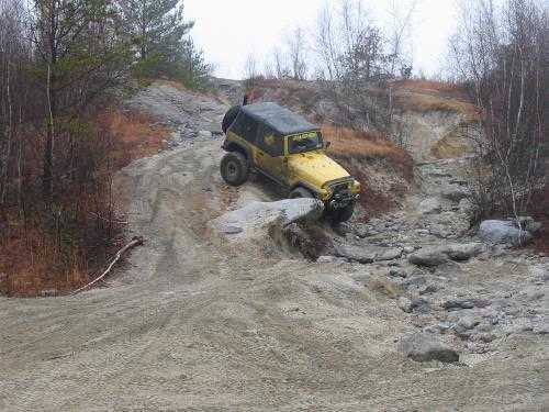 Yellow Jeep navigating rocky terrain