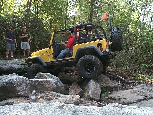 Yellow Jeep navigating rocks, off-road adventure