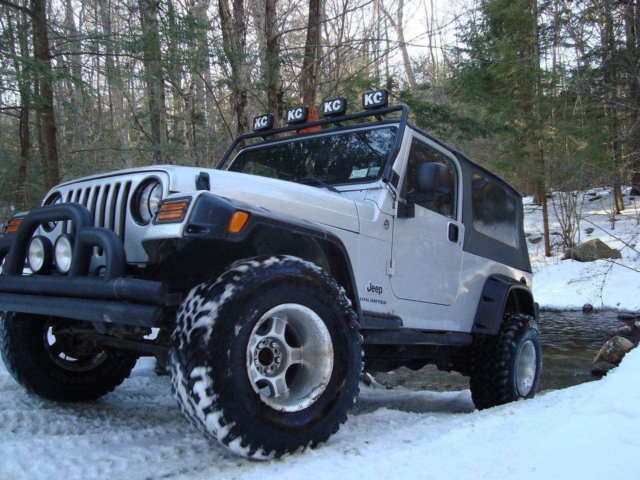 Silver Jeep Wrangler in snowy woods
