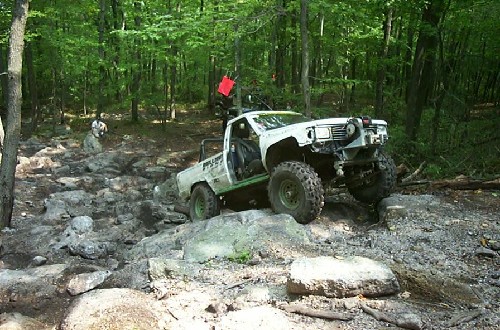 White Toyota pickup truck off-roading on rocks