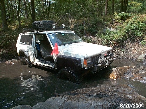 White Jeep Cherokee off-roading in mud