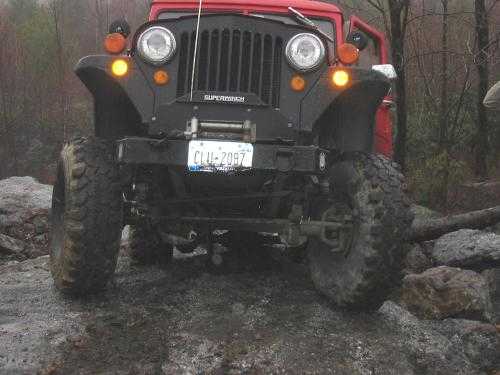 Red Jeep traversing muddy trail