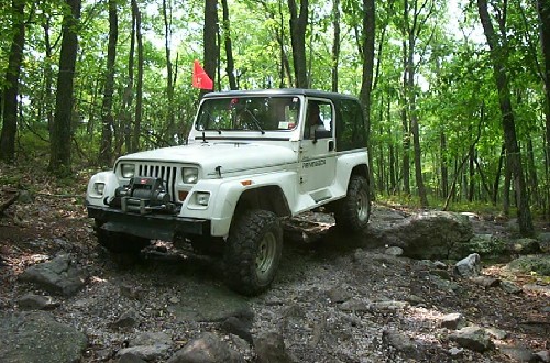 White Jeep Wrangler off-roading on rocky trail
