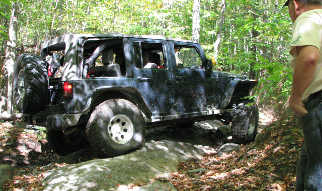 Black Jeep Wrangler traversing rocky terrain