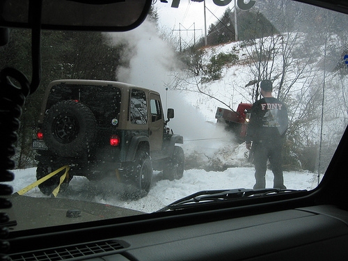 Tan Jeep stuck in snowy terrain; recovery in progress